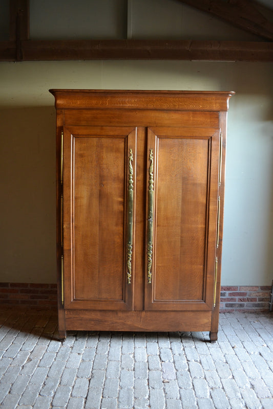 Antieke strakke eiken houten Louis Philippe kast met twee deuren voorzien van panelen en grote messing scharnieren en beslag. Achter de deuren planken en laden. Antiek kledingkast, antieke linnenkast, antieke opbergkast, antieke Franse kast, antieke eiken kast, antieke woonkamerkast, antieke slaapkamerkast.